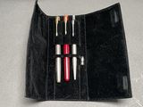 a black wallet with a red pen and two pens in it
