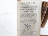 an old book on a table with a bunch of books in the background