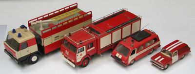 quatre camions de pompiers miniatures et un vrai camion de pompiers posés sur une table