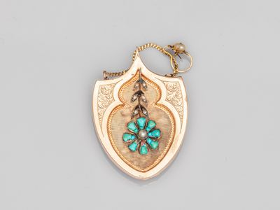 un gros plan d'un pendentif en or et turquoise monté sur une chaîne