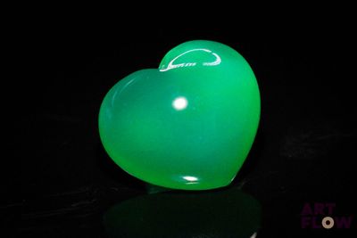 a green heart shaped balloon sitting on a black surface