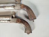 pair of antique silver plated pistols on a white surface