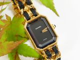 a black and gold watch sitting on a chain bracelet