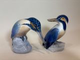two figurines of birds that are sitting on a rock