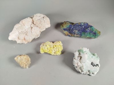 several different colored rocks on a white surface with a gray background