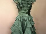 robe verte à volants posée sur un mannequin devant un mur rose