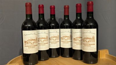 four bottles of wine are lined up on a wooden barrel