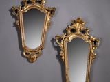 deux miroirs dorés ornés de motifs élaborés, posés contre un mur gris
