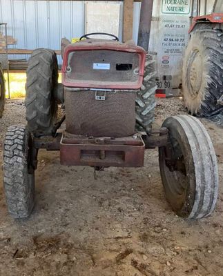 un tracteur qui est à l'abandon dans la boue, dans une grange