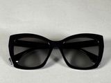 un gros plan sur une paire de lunettes de soleil noires posées sur une surface blanche