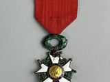 une image représentant une médaille ornée d'une étoile, suspendue à un ruban rouge