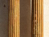 pair of antique brass columns on a white wall with a shadow