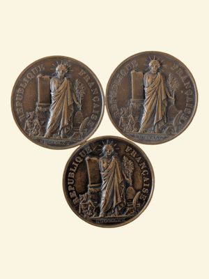 three bronze coins with a statue of a woman and a man on them