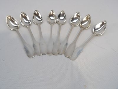 six cuillères en argent sont alignées sur une surface blanche