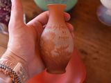 a person holding a small vase with writing on it
