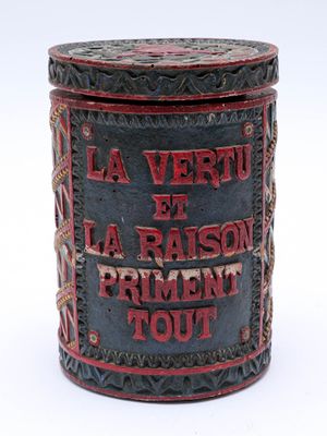une vieille boîte en fer-blanc sur laquelle sont inscrits les mots « la vertu et la raison »