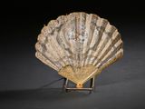 une image représentant un objet en forme de coquillage posé sur un socle, sur une surface noire