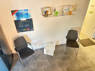 deux chaises dans un coin d'une pièce où sont accrochés des tableaux au mur