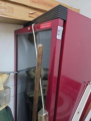 un réfrigérateur rouge dans lequel se trouve une batte de baseball