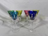 quatre verres à vin colorés posés sur une table blanche