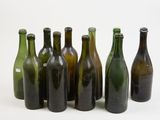 several empty wine bottles lined up in a row on a white surface