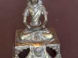 statue en argent représentant une personne assise sur une table, devant un bol de nourriture