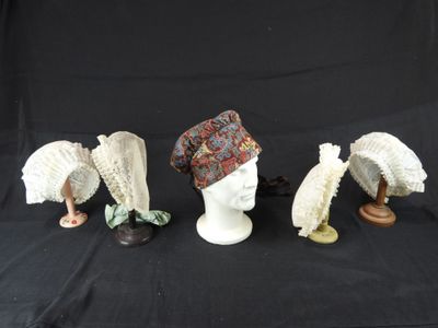 trois chapeaux et un porte-chapeaux sur fond noir