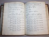 an old open book with writing on it sitting on a table