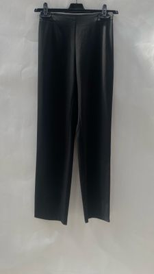 a black leather pants hanging on a hanger on a wall