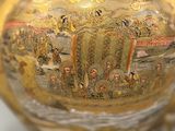 a gold vase with a painting on it sitting on a table