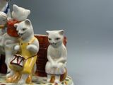 une figurine représentant trois chats assis sur un banc