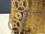 a gold clock with gears on a stand on a table