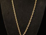 a necklace with a gold chain and a small pendant with a white diamond