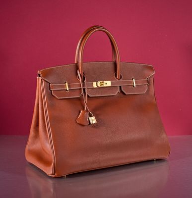 a brown leather handbag sitting on top of a table next to a red wall