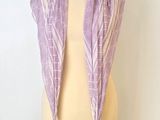 une écharpe violette posée sur un présentoir à mannequin, sur fond blanc