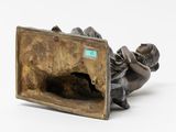 a bronze figurine of a boy laying on the ground