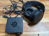 a black box with headphones and a charger on a wooden table