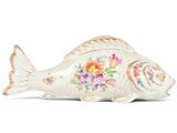 a white fish with flowers on it sitting on a white surface
