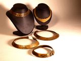 three pieces of jewelry on display on a white surface