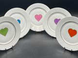 four plates with hearts painted on them sitting on a table