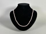 a white pearl necklace on a black mannequin