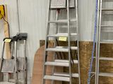 Plusieurs échelles sont alignées contre un mur dans un entrepôt.