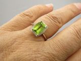 une image représentant la main d'une personne portant une bague sertie d'une pierre verte