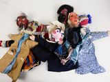 five cloth dolls of different colors and sizes on a white surface