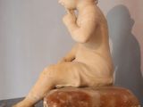 marble statue of a boy sitting on a rock with his hand on his chin