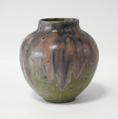 un vase marron et vert posé sur une surface blanche