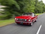 a red car driving down the road with trees in the background