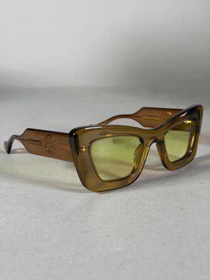 des lunettes de soleil marron aux verres verts posées sur une surface blanche