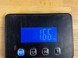 a digital clock on a wooden table with a charger plugged into it
