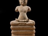 une statue de Bouddha assis au sommet d'un tas de pierres